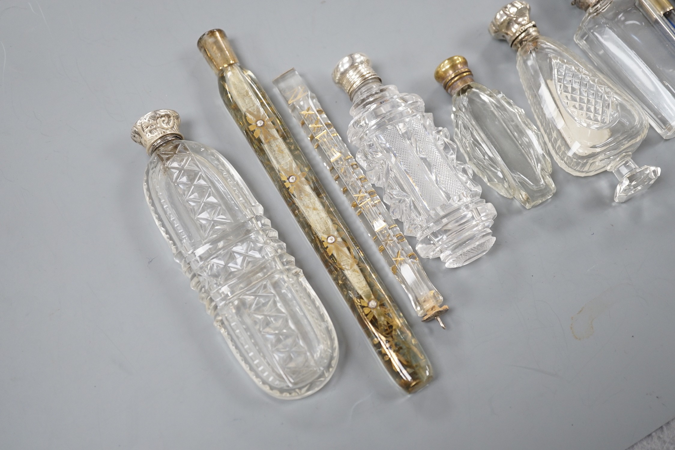Nine assorted late 19th/early 20th century white or gilt white metal mounted glass scent bottles, including Austro-Hungarian gilt white metal and enamel mounted cylindrical scent by George Adam Scheid, largest 17.2cm.